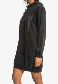 Robe à capuche noire avec une coupe décontractée, dotée d'une poche avant, de détails en logo texturé et de poignets côtelés. Tissu doux et lisse.