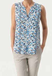Květinová bezramínková blůza s modro-bílým vzorem, výstřihem do V, lehkým materiálem a uvolněným střihem. Slaďte s béžovými kalhotami.
