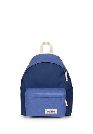 Sac à dos en tissu bleu avec poche zippée à l'avant, languettes blanches et poignée supérieure beige sur fond blanc.