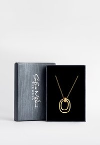 Guld vedhængs halskæde med sammenkoblede cirkulære former og et design prydet med diamanter, præsenteret i en kasse med sort fløjl.