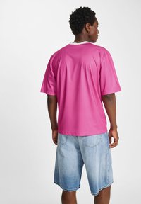 Kortärmad, ljusrosa t-shirt med vit krage, ribbad textur, avslappnad passform, kombinerad med ljusblå denimshorts.