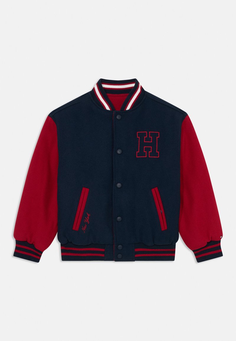 Ναυτικό και κόκκινο τζάκετ πανεπιστημίου με λογότυπο "H" στο στήθος, ριγέ κολάρο και δύο κόκκινες πλαϊνές τσέπες. Διαθέτει ελαστικές μανσέτες και μέση.