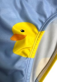 Un maillot de bain bleu clair avec un motif de canard en caoutchouc jaune, des détails de bec orange et une texture de tissu lisse et brillant.