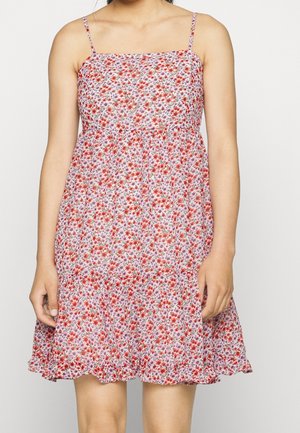 Kukkakuvioinen mekko, jossa on neliömäinen pääntie, ohuet hihnat ja levenevä helma. Kangas on vaaleanpunainen, ja siinä on punaisia ja purppuranvärisiä kukkakuoseja.