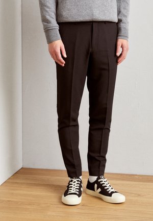 Pantalon noir au design ajusté, avec une texture douce et une coupe fuselée, associé à des baskets noir et blanc.