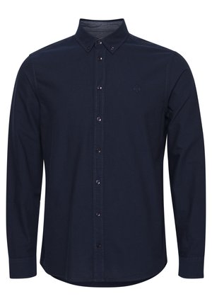 Chemise à manches longues bleu marine avec col boutonné, présentant une patte de boutonnage, un logo discret sur la poitrine et un ourlet arrondi.