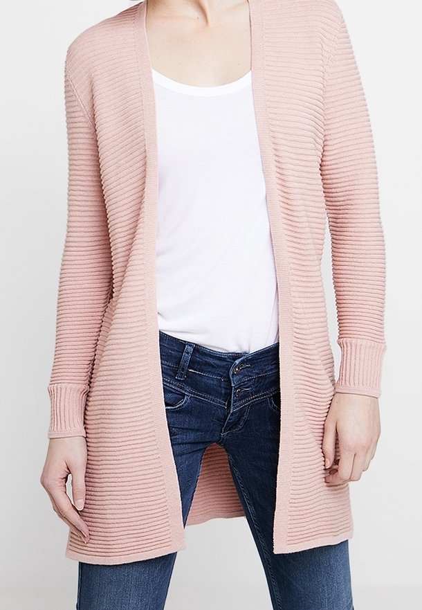 Cardigan rigato rosa chiaro con apertura frontale, maniche lunghe e texture morbida, abbinato a una t-shirt bianca e jeans blu.