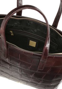 Burgundy läderväska med krokodilstruktur, dubbla handtag, blixtlåsstängning och en svart innerfoder med logomönster.
