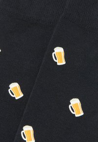 Tela oscura con íconos de pequeñas jarras de cerveza que se repiten, llenas de líquido ámbar y con una capa espumosa blanca en la parte superior.