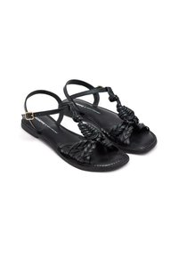 Sandales noires avec un design tressé sur le bout, sangle de cheville ajustable, semelle plate et accents matériels minimalistes. Matériau en cuir durable.