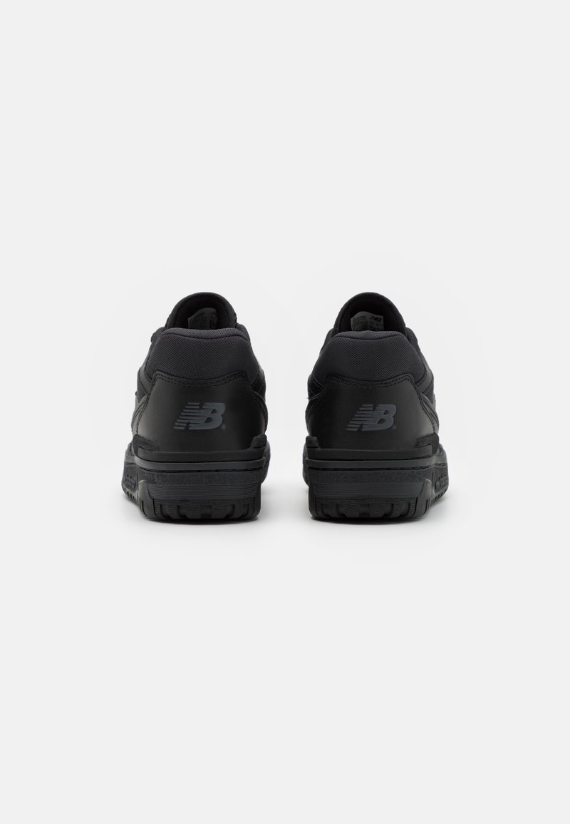 Baskets de sport noires avec un col rembourré, un design élégant, une tige en cuir texturé et une semelle en caoutchouc robuste, présentant un logo discret sur les talons.