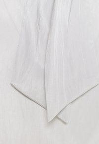 Bílá látka s hladkým, hedvábným povrchem. Vyznačuje se jemným leskem a delikátními vráskami. Okraje jsou lehce přehnuté, čímž vykazují čistý a úhledný vzhled.