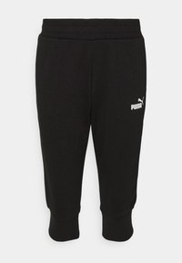 Calças de treino pretas com um cós canelado, comprimento cropped, e o logo da PUMA em branco no lado esquerdo. Textura suave e ajuste solto.