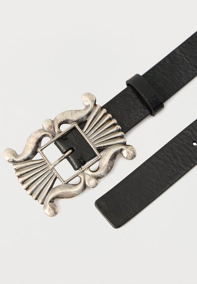Μαύρη δερμάτινη ζώνη με διακοσμητική αγκράφα από ασημί μέταλλο, που διαθέτει σχέδιο κοχυλιού και περίτεχνα άκρα. Λείο υλικό, ρυθμιζόμενο μήκος.