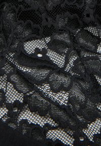 Svart spetstyg med blommönster och en fin nätliknande textur. Designen inkluderar intrikata detaljer med varierande former och storlekar.
