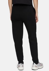 Zwarte katoenen sweatpants met een slim fit, voorzien van zijzakken en geribbelde boorden, gecombineerd met grijze en rode sport schoenen.