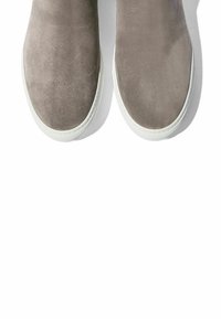 Zapatos de ante gris de tipo slip-on con una textura suave y punta redonda, que presentan una suela de goma blanca y un diseño minimalista.