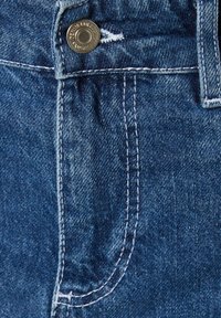 Mörkblå denimtyg med en metallknapp och kontrasterande vit sömnad. Närbild visar fickans kontur och texturdetaljer.