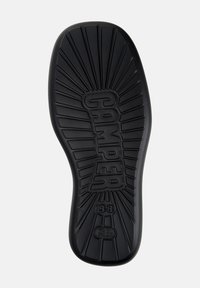 Suela de zapato de goma negra con una superficie texturizada, que presenta un patrón de destello solar y "CAMPE" grabado en el centro con el tamaño "38" visible.