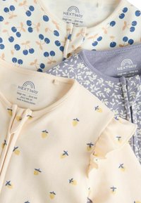 Trois bodies pour bébés en coton doux : un avec un imprimé cerise sur crème, un avec des motifs de citron sur rose pastel, et un avec un motif floral sur violet clair.