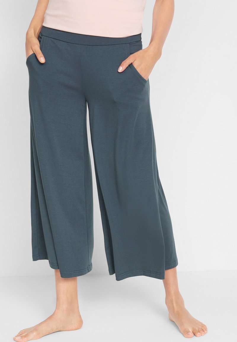Pantaloni a gamba larga realizzati in morbido tessuto color teal scuro, con una cintura elastica e tasche laterali, dalla texture liscia e design alla caviglia.