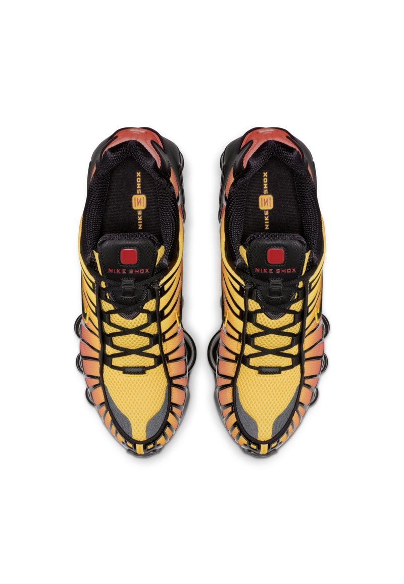 Baskets Nike Shox en jaune et noir avec une tige en maille texturée, des accents en caoutchouc et une semelle distinctive amortissante.