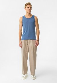 Blauwe katoenen tanktop met een ronde hals, gecombineerd met beige, geplooide broeken en witte sneakers. Eenvoudig ontwerp en een relaxte pasvorm.