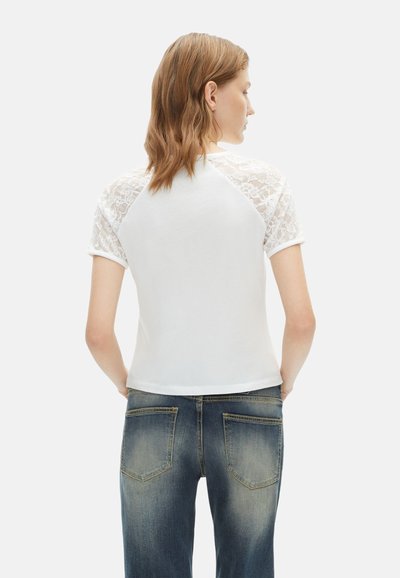 Witte t-shirt met korte kanten mouwen en een ronde halslijn, gecombineerd met blauwe jeans. Eenvoudig ontwerp met een losse pasvorm.