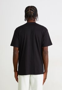 Black cotton t-shirt with a relaxed fit, short sleeves, and a crew neckline. Simple design without patterns or accents.