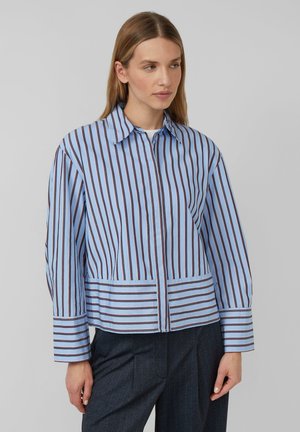Chemise en coton bleu avec des rayures verticales brunes, un devant boutonné, un col pointu et des manches longues. Présente une coupe courte et décontractée.