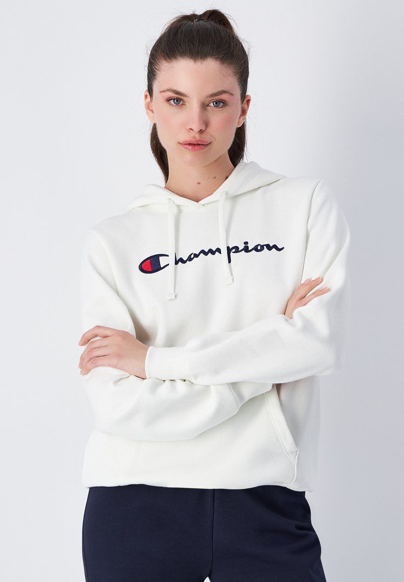 Sudadera blanca de algodón con un bolsillo tipo canguro en el frente, capucha ajustable con cordón y logo bordado de "Champion" en azul marino y rojo.