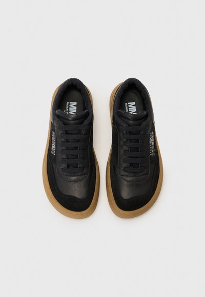 Svarta lädersneakers i mocka med gummisula, rund snörning, vadderade kragar och logotypdetaljer på sidan och tungan.