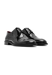 Chaussures de mariage en cuir verni noir avec une surface lisse, bout arrondi, fermeture à lacets à huit œillets et talon empilé.