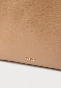 Lys cognacfarvet lædertaske med tekstureret overflade. Har en lille "Furla"-logo i guld nederst til højre.