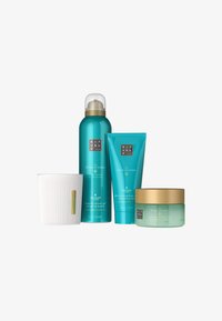 Set med fyra Ritual of Karma hudvårdsprodukter som inkluderar ett skummande duschgel, en återfuktande kroppskräm, en kroppsskrubb och ett vitt ribbat doftljus.