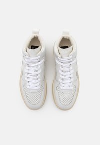 Baskets en cuir blanc avec bout perforé, lacets blancs et semelle beige vues de dessus sur un fond clair.