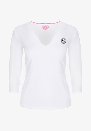 Camiseta blanca de manga larga para mujer con escote en V, con un pequeño logo circular negro en el pecho izquierdo y un detalle interior del cuello en color rosa.