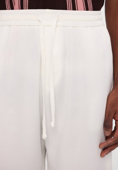 White elastic waist pants with external drawstring, featuring a smooth texture and a relaxed fit. The waistband is gathered for added comfort.