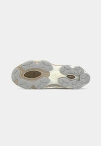 Sport shoe sole with a combination of beige and gray rubber; features unique traction patterns and textured details for grip.