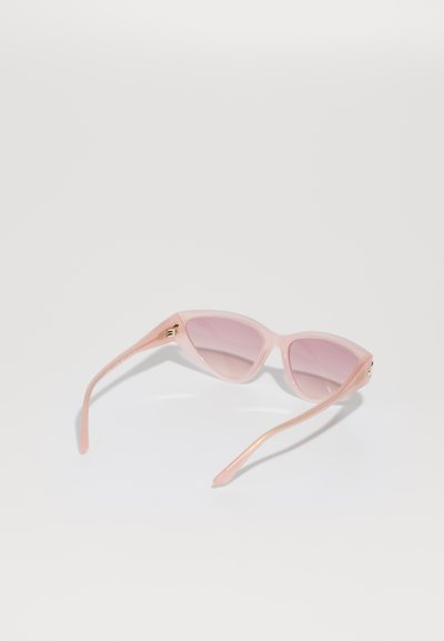 Pink sunglasses with a slim, cat-eye design. Made from translucent plastic with gradient lenses and subtle gold hardware accents.