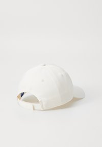 White cotton baseball cap with a rounded crown, a curved brim, and an adjustable strap at the back. Smooth texture, minimal detailing.