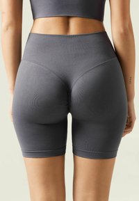 Grå, ribbade högmidjade shorts med en figurnära design som har rynkningar bak. Slät textur med knälång längd.