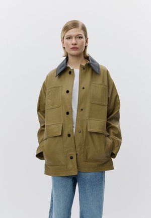 Olivengroene oversized jas met een zwarte leren kraag, voorzien van vier zakken met klep en knoopsluitingen, gemaakt van een glad, duurzaam materiaal.