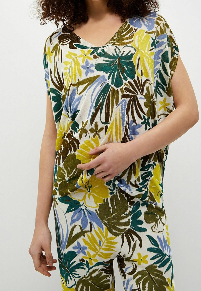 Top de manga corta y escote en V con un estampado floral en amarillo, azul, verde y marrón sobre un fondo claro, fabricado en una tela suave y texturizada.