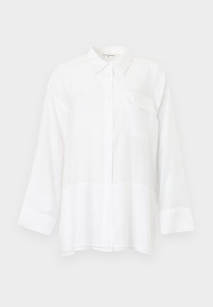 Camisa blanca de botones hecha de tela ligera, con mangas largas, un bolsillo en el pecho y una textura ligeramente translúcida.