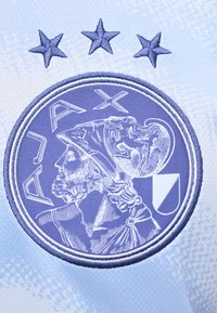 Logo ricamato del club di calcio Ajax che mostra una figura classica elmetata di profilo con tre stelle sopra su tessuto azzurro chiaro.