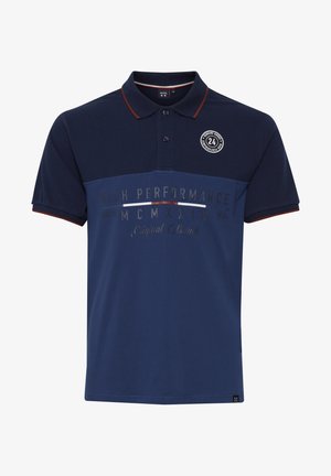 Tengerészkék pólóing piros kiemelt gallérral. Vízszintes színblokkal és "MAGAS TELJESÍTMÉNY" felirattal, valamint egy kör alakú logóval a mellkason.