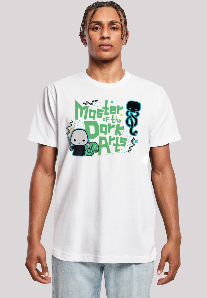 Camiseta de algodón blanca con un diseño gráfico colorido que incluye el texto "Maestro de las Artes Oscuras", figuras de dibujos animados y acentos abstractos.