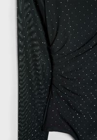 Schwarzes Stoffoberteil mit strukturiertem Finish, das mit verstreuten silbernen Rhinestones verziert ist. Mit Raffung an der Seite für zusätzliche Dimension.