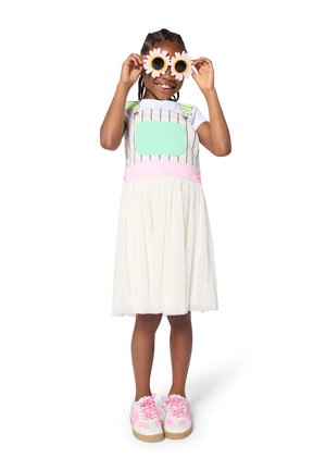 Meerlagige jurk met een gestreept bovenstuk, een groen zakje en een roze tailleband. Tulle rok, gecombineerd met roze sneakers met bloemenaccenten.